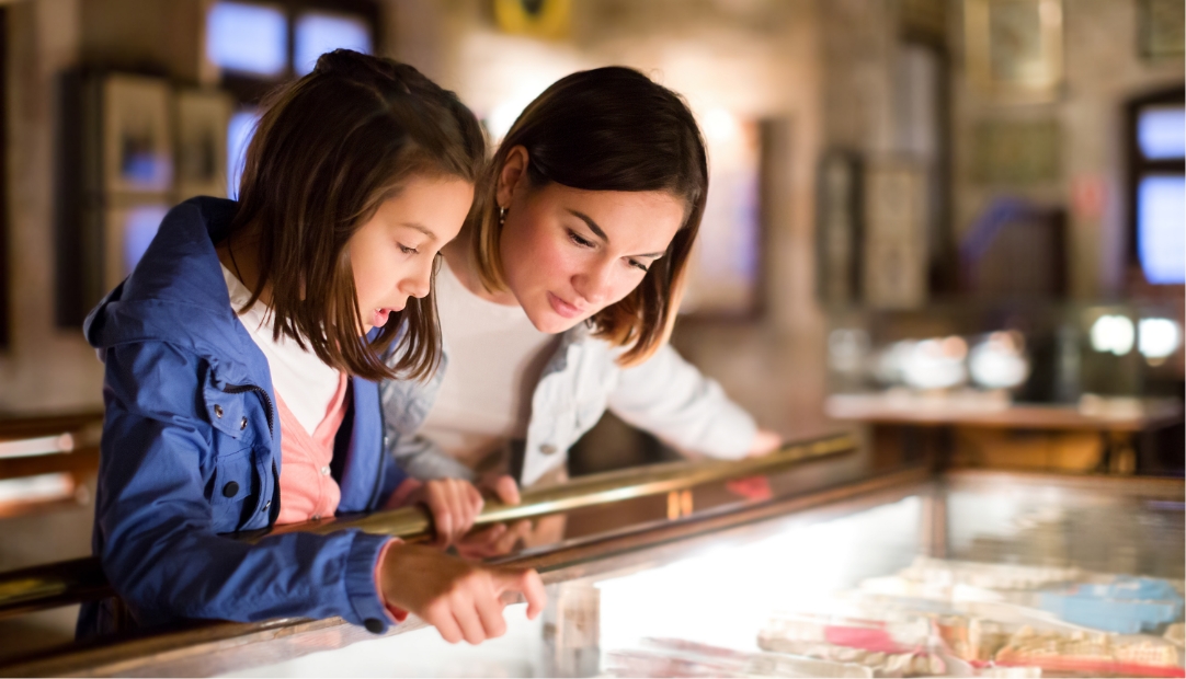 A mother and daughter look through a retail store display case.