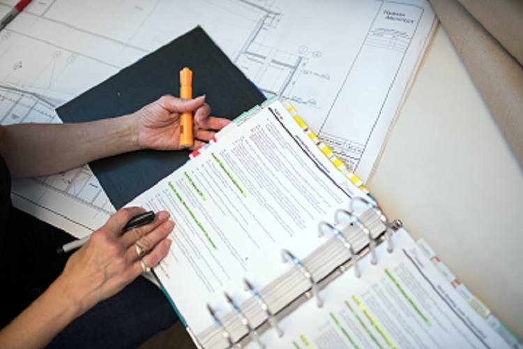 A worker highlights notes in a construction document.