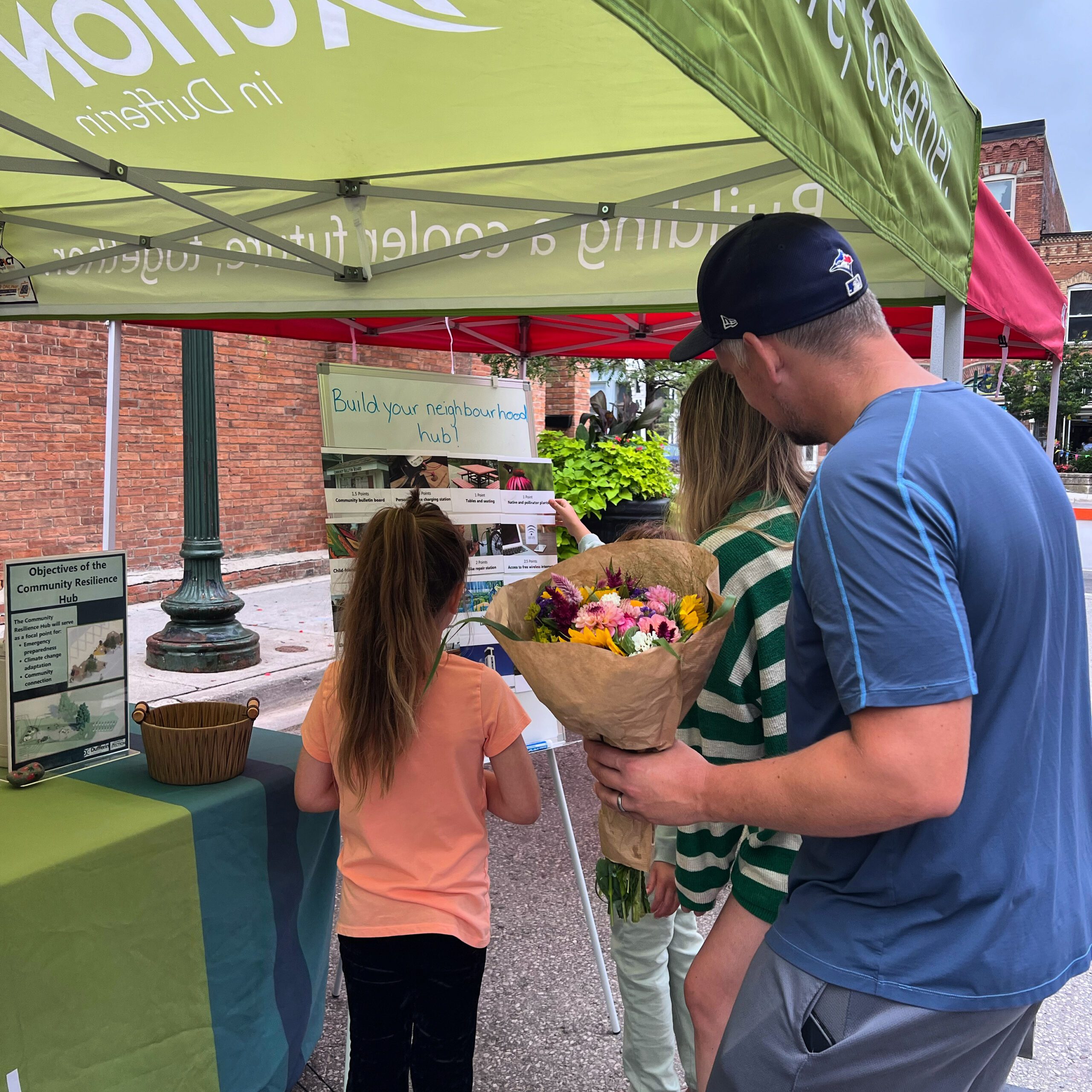 A family looks at a booth featuring a sign on creating your own outdoor community hub