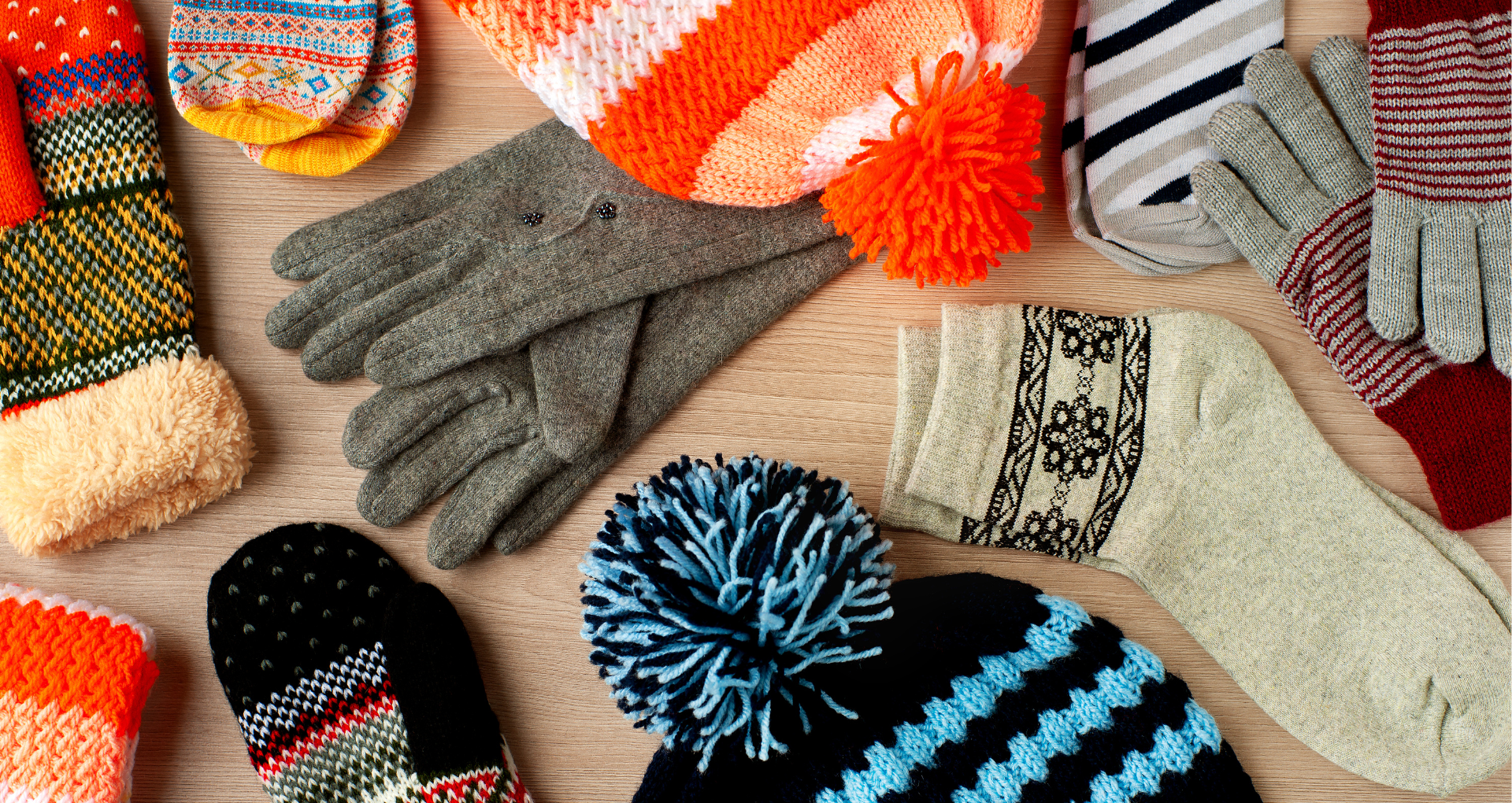 winter accessories including hats, socks, mittens and gloves on a table.