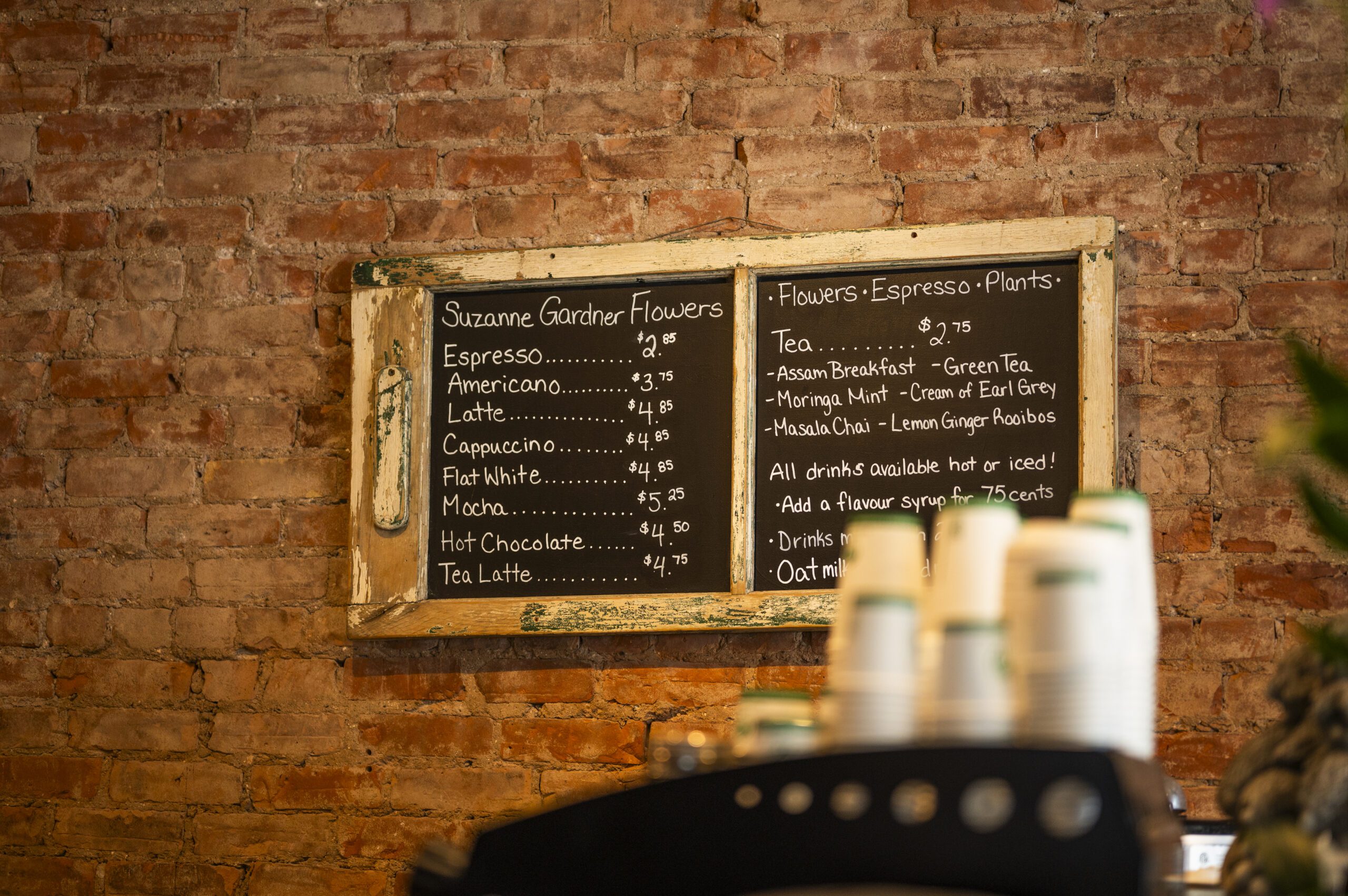 Chalkboard menu in cafe with brick wall behind.